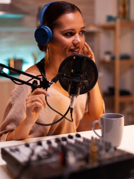 Creative influencer with headphones speaking with fans during live on social media using professional gear. On-air online production internet broadcast show host streaming live content